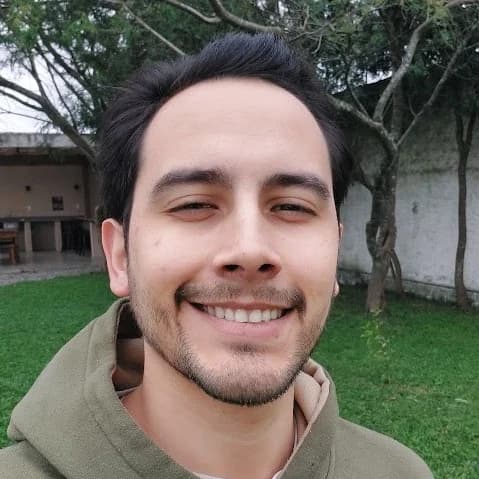 Gabriel, de moletom verde-oliva, sorrindo ao ar livre.